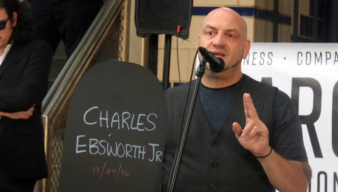 Elvis Rosado, 52, giving a speech to the gathered crowd as he holds the name of a loved one who has died due to an overdose.  