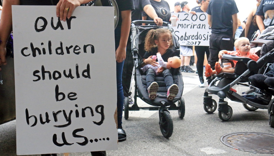 A march participant holds a sign with the words “Our children should be burying us…” written on it.