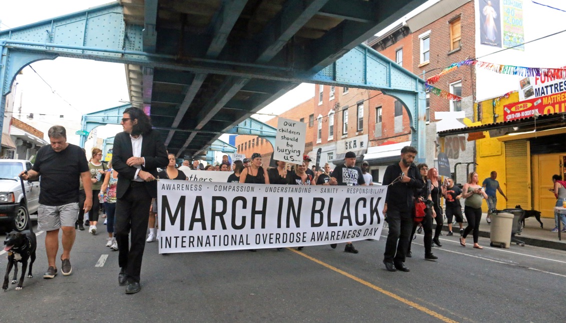 Jose de Marco of ACT UP Philadelphia and Dan Martino hold the “March In Black” as they lead the march down Kensington avenue towards Huntington station. 